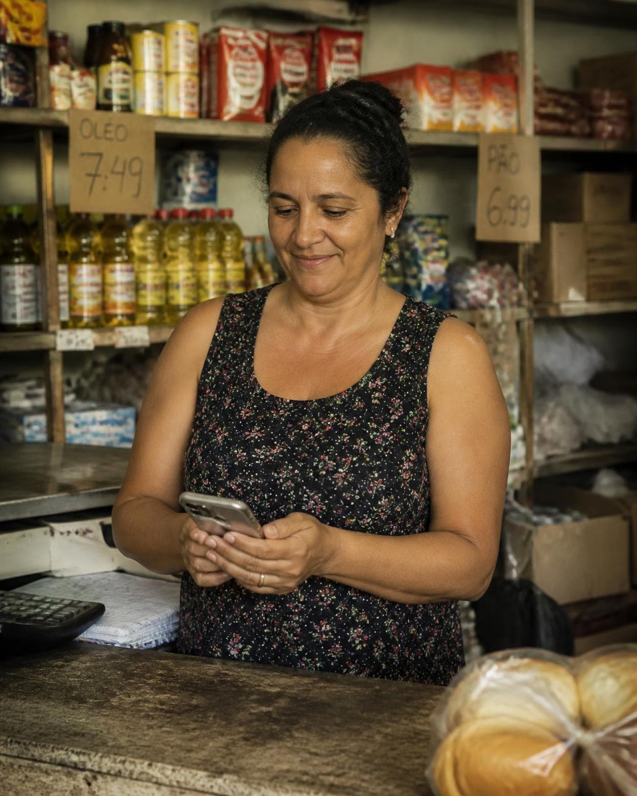 Dona de mercadinho conferindo o estoque com o celular na mão
